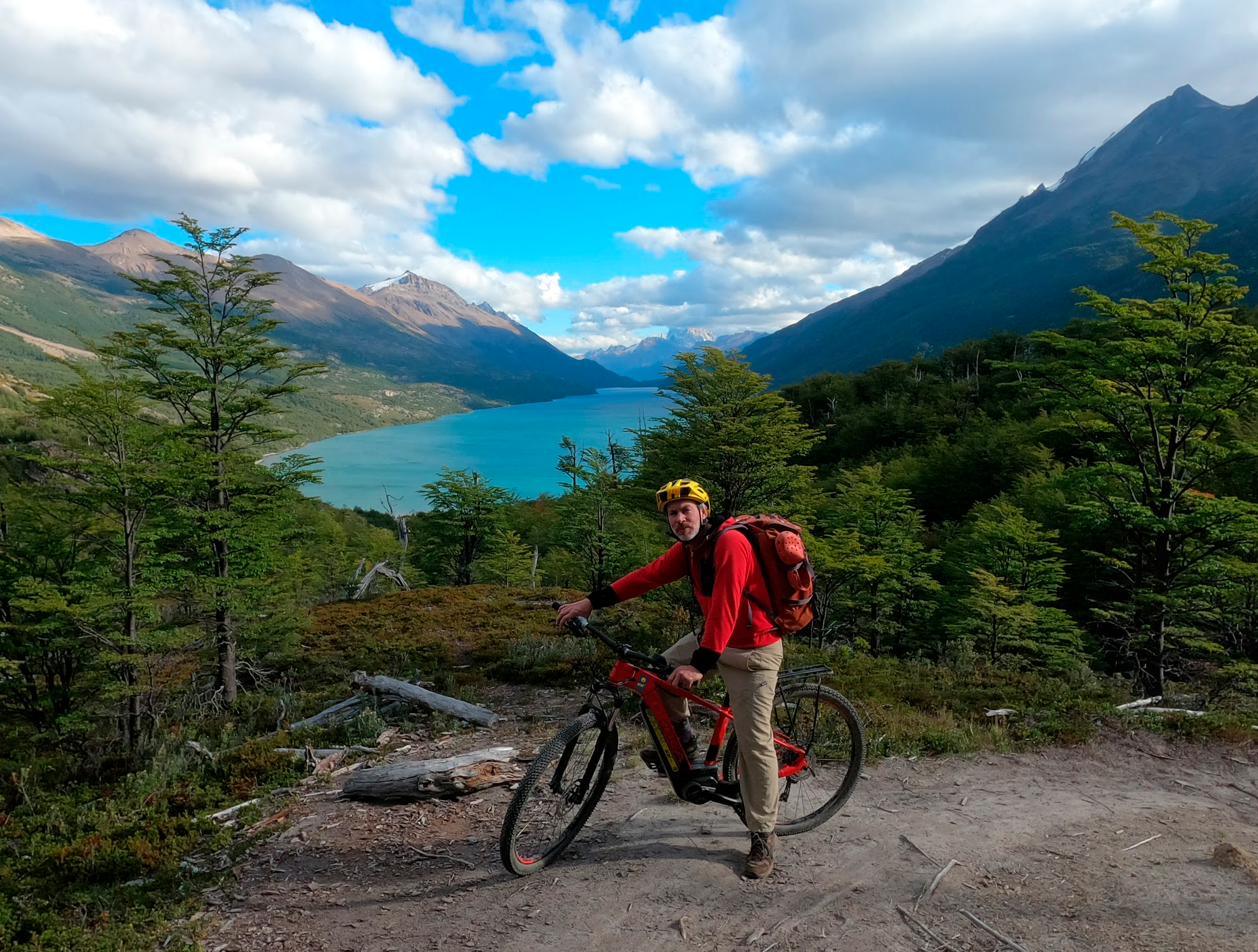 Un ciclista con su e-bike en el sendero, con el Lago del Desierto y la cordillera detrás