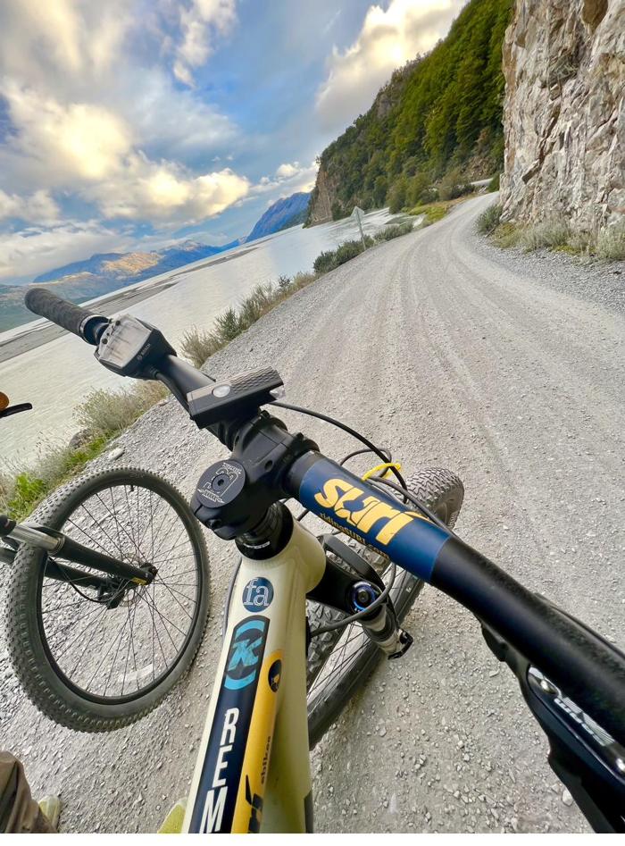Manubrio de una e-bike de SURí sobre el ripio de la Carretera Austral, junto al lago