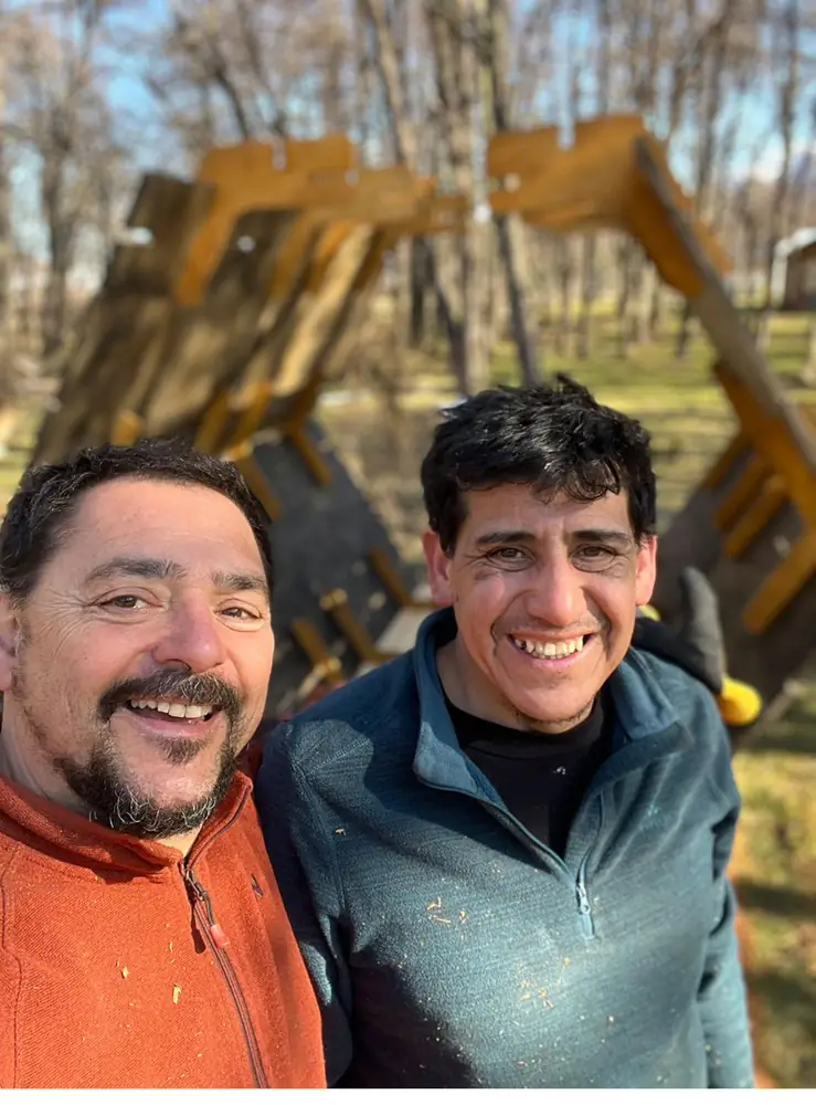 Javi y Pachi sonríen frente a un micro-refugio en el camping de Villa O'Higgins