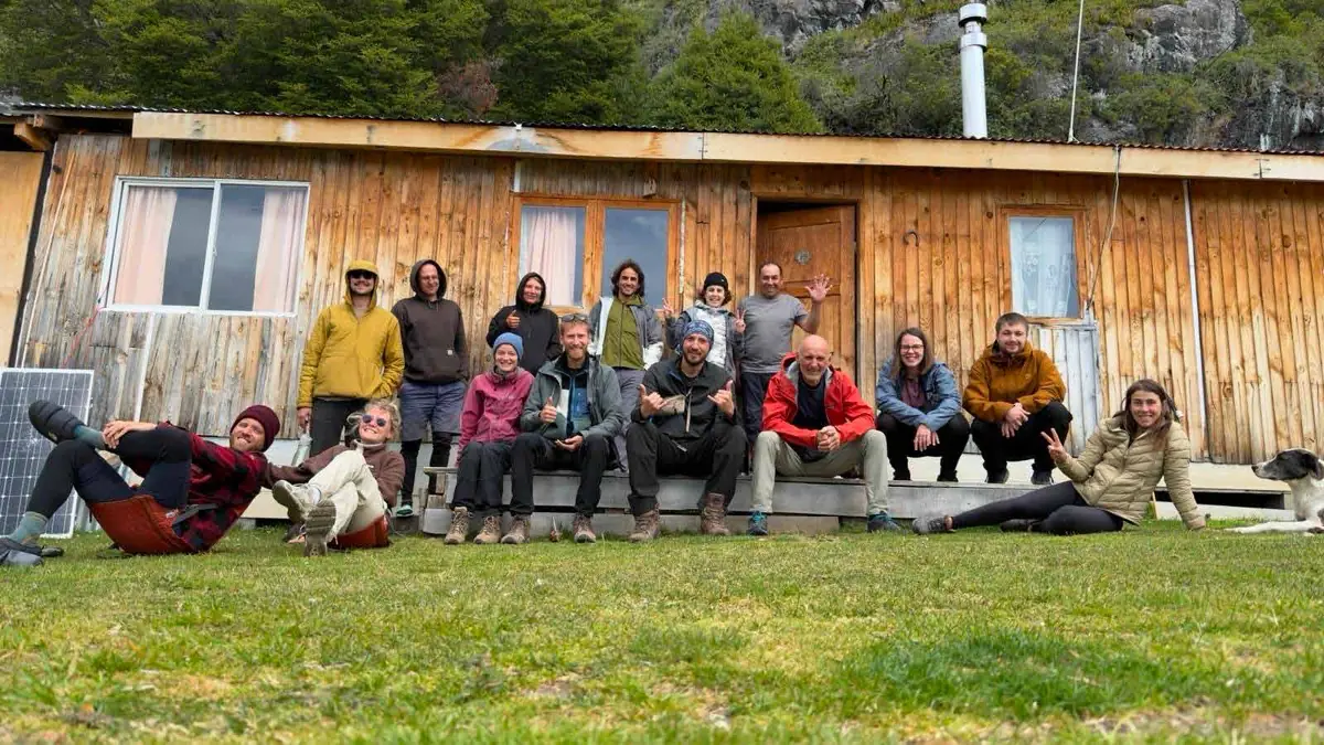 Un grupo de viajeros sentados frente a una casa de madera en Candelario Mancilla