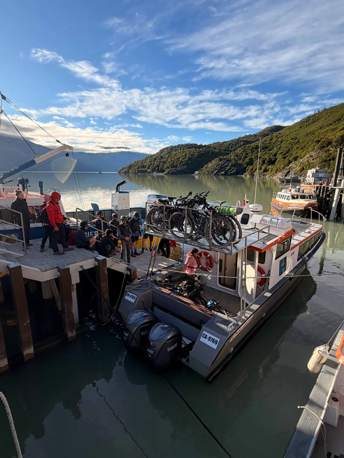 Una embarcación de Ruedas de la Patagonia amarrada en el muelle, con bicicletas a bordo